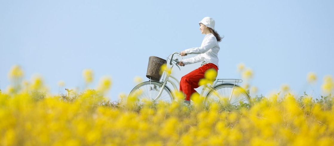 A young woman rides a bicycle through a summer field